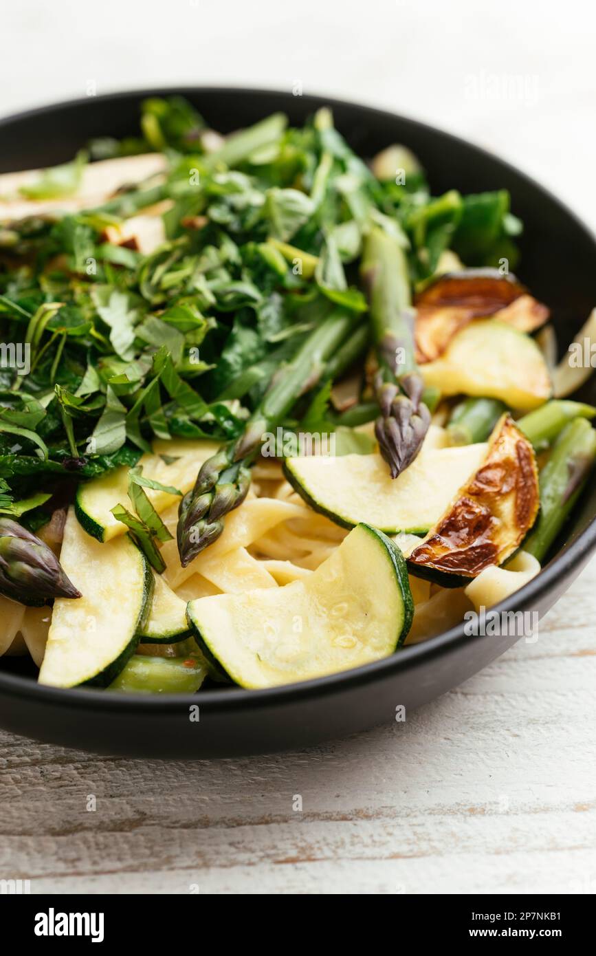 Bowl with home made tagliatelle with green asparagus, zucchini and spinach. Stock Photo