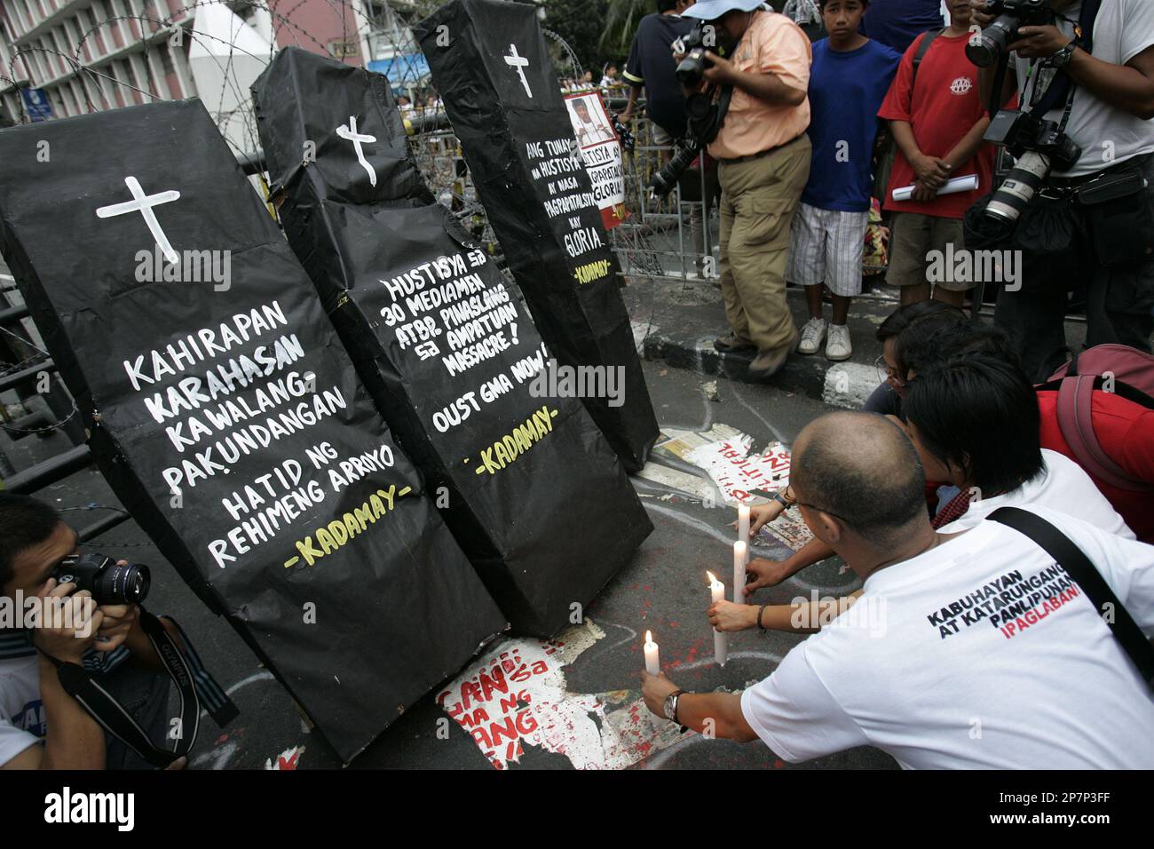 Filipino activists light candles in front of mock coffins which is painted with slogans denouncing injustice and violence under President Gloria Macapagal Arroyo and demanding justice for massacre victims during a rally near the Malacanang presidential palace in Manila, Philippines on Thursday Dec. 3, 2009. The group is condemning the Philippines' worst political massacre which killed 57 people, more than half of them journalist. The powerful Ampatuan clan, which is an ally of Philippine President Gloria Macapagal Arroyo, is being blamed for the mass killings. (AP Photo/Aaron Favila) Stock Photo