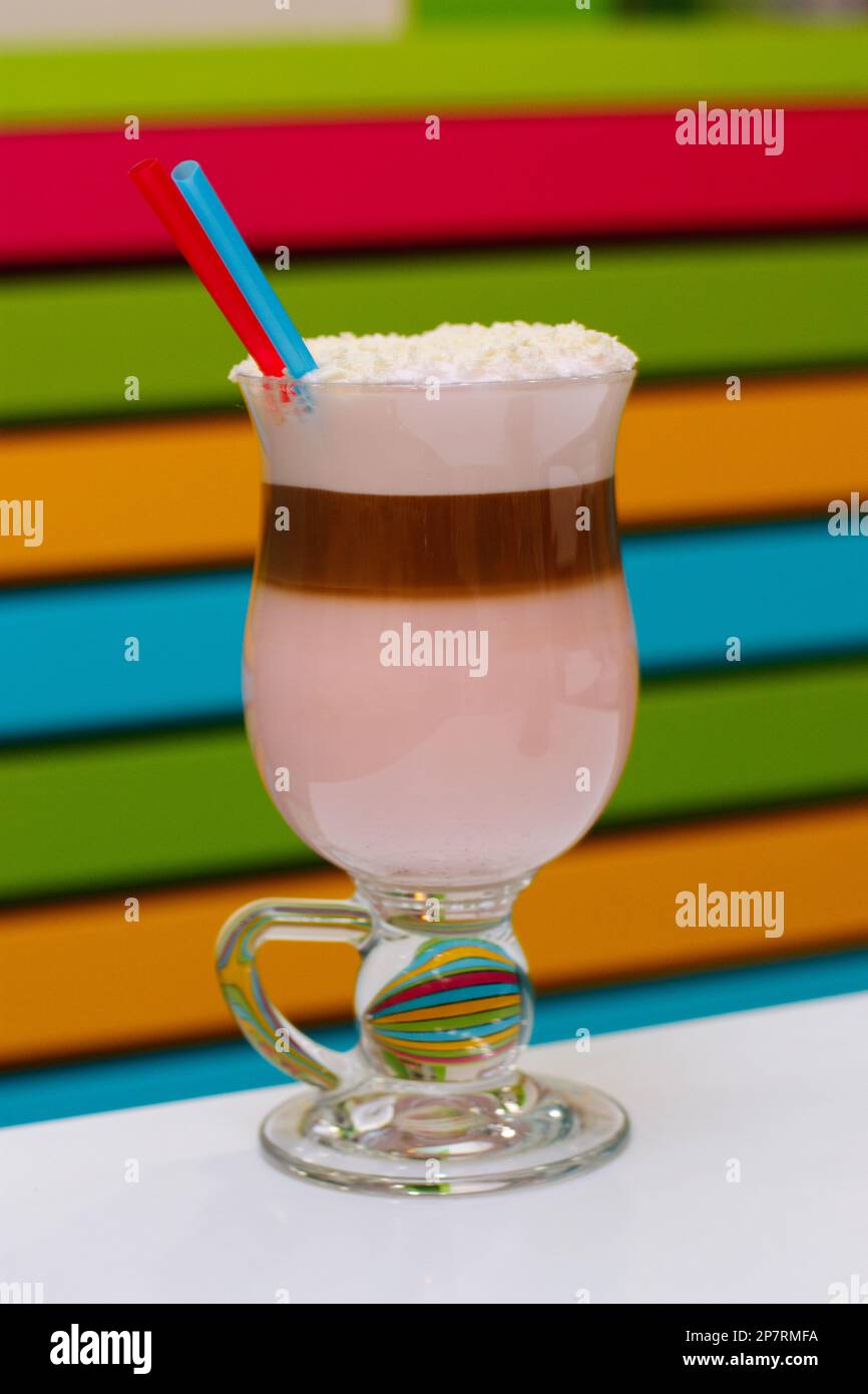 Coffee cocktail with foam and coconut flakes with two straws. Colorful and striped background Stock Photo