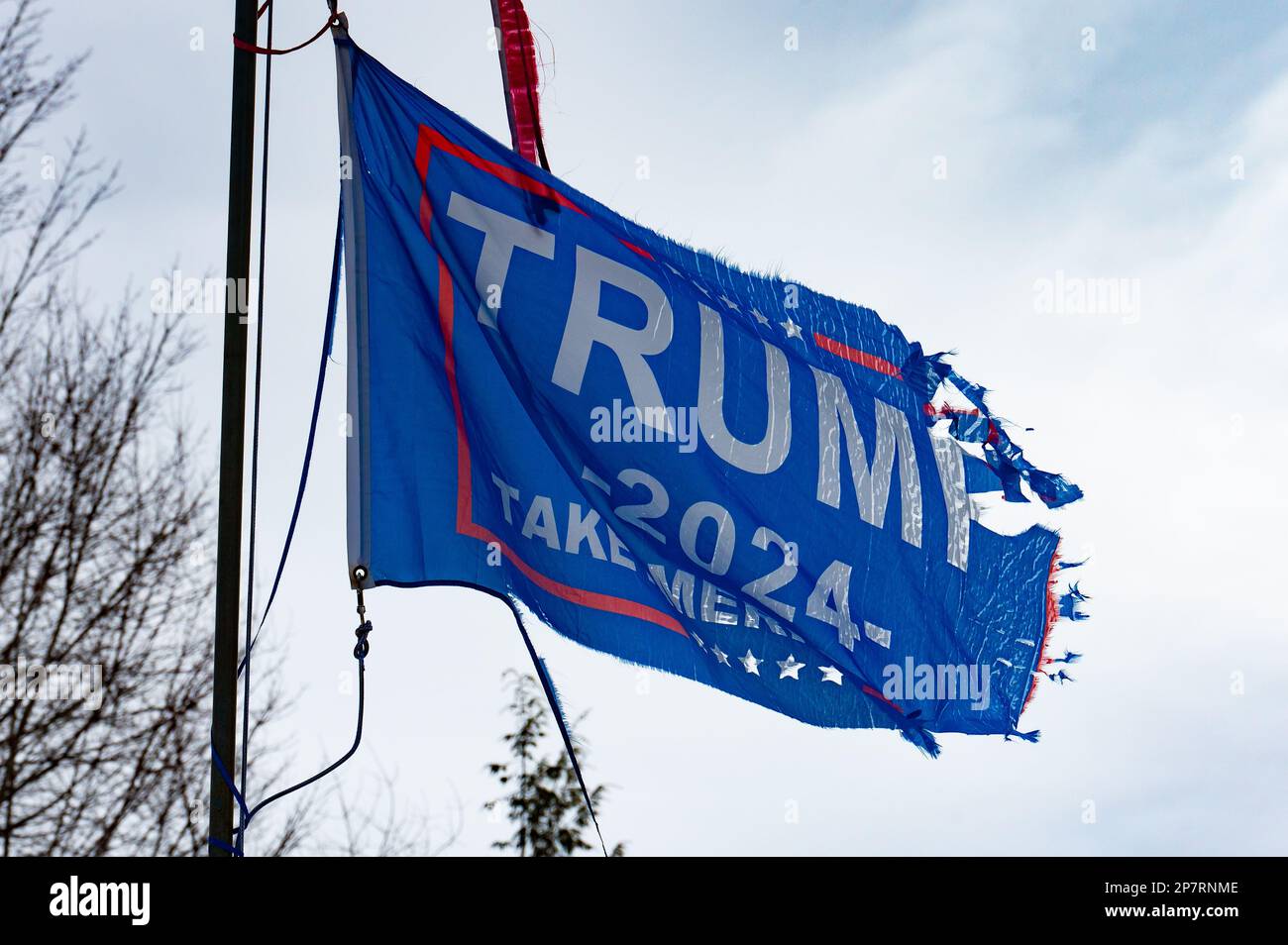 A red white and blue faded ragged torn Trump 2004 flag blowing in the wind Stock Photo
