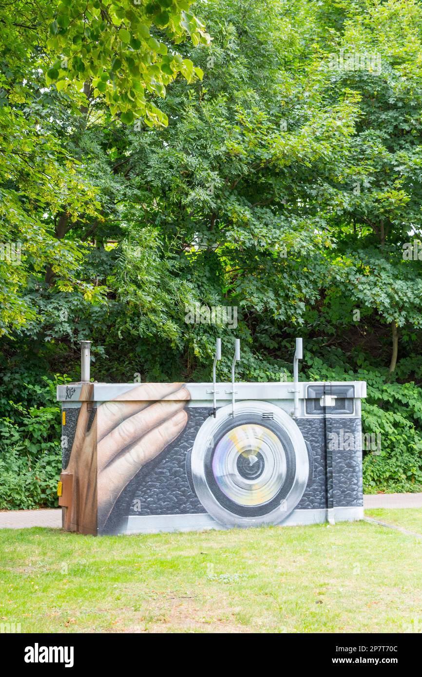 A gas pressure regulator station in Hamburg in a meadow, painted with graffiti that makes the structure look like a giant historical photo camera Stock Photo
