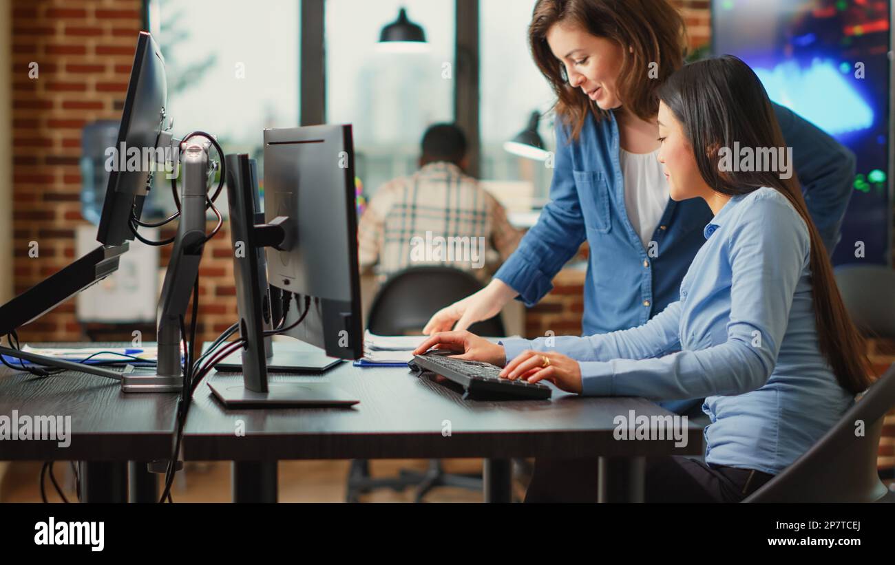 Female app developers working on software production with multiple displays, using computers interface to develop new professional content. Creative agency workers creating 3d scene project. Stock Photo