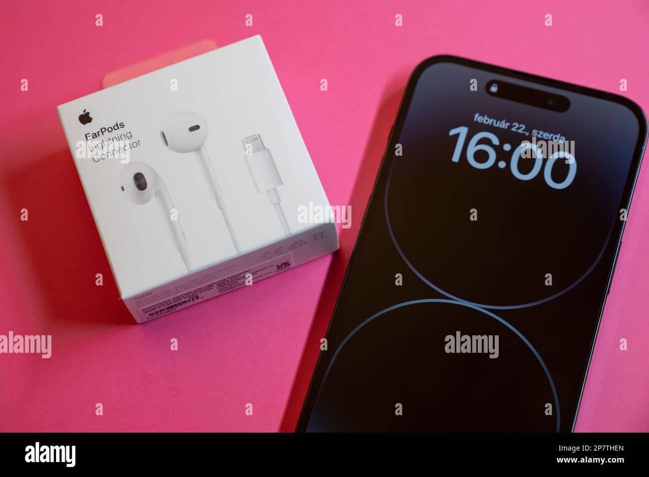 New iPhone 14 pro max and Apple Earpods, Airpods white earphones for listening to music and podcasts, in a closed box. Isolated pink background. Budap Stock Photo