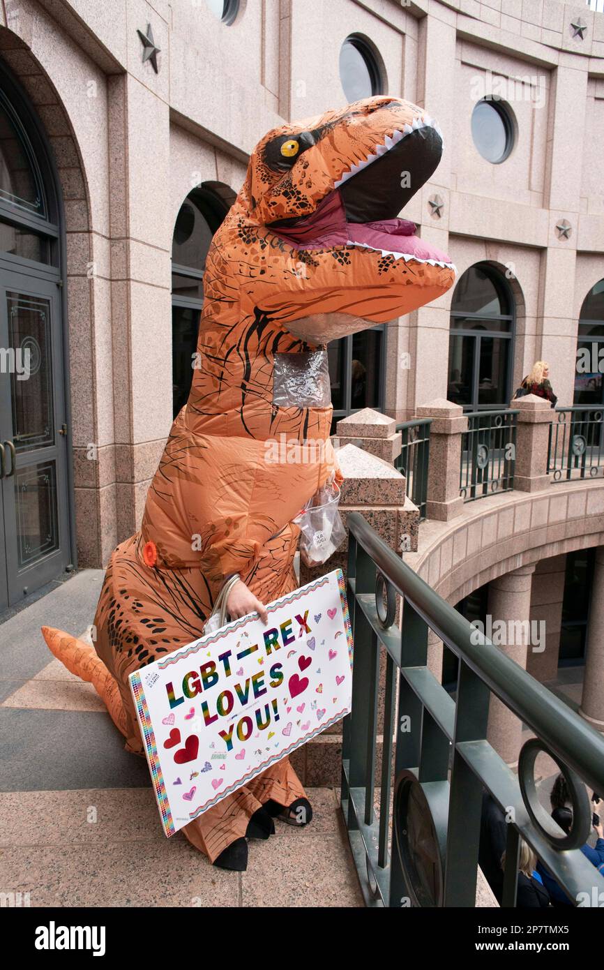 A person dressed in a T-Rex dinosaur costume holds a sign saying 'LGBT-Rex Loves You' as a group from The Organization of Latina Transgender Texans (OLTT) lobbied for transgender rights during a trip to the Texas Capitol to visit with legislators. Credit: Bob Daemmrich/Alamy Live News Stock Photo