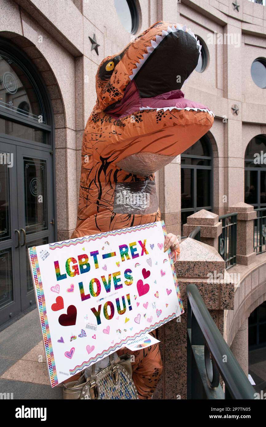 A person dressed in a T-Rex dinosaur costume holds a sign saying 'LGBT-Rex Loves You' as a group from The Organization of Latina Transgender Texans (OLTT) lobbied for transgender rights during a trip to the Texas Capitol to visit with legislators. Credit: Bob Daemmrich/Alamy Live News Stock Photo