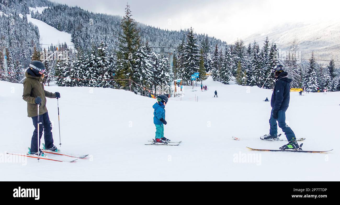 Adults with child on ski slopes Stock Photo