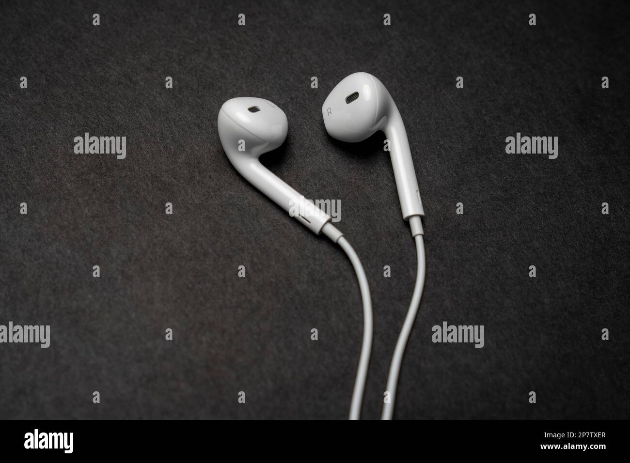 iPhone Apple Earpods, Airpods white earphones, headphones for listening to music and podcasts. Isolated black background. Stock Photo