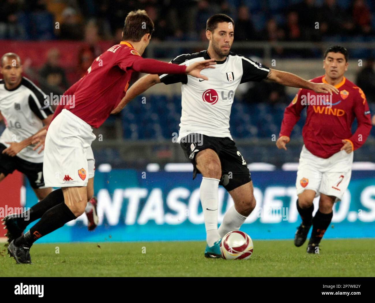 Fulham' s Clint Dempsey, center, dribbles past AS Roma's Marco