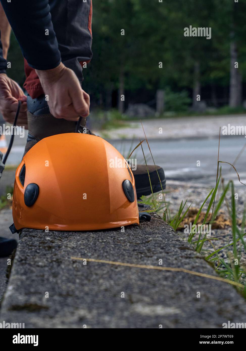 Mountain rock climber preparing for climbing lacing his shoes leather