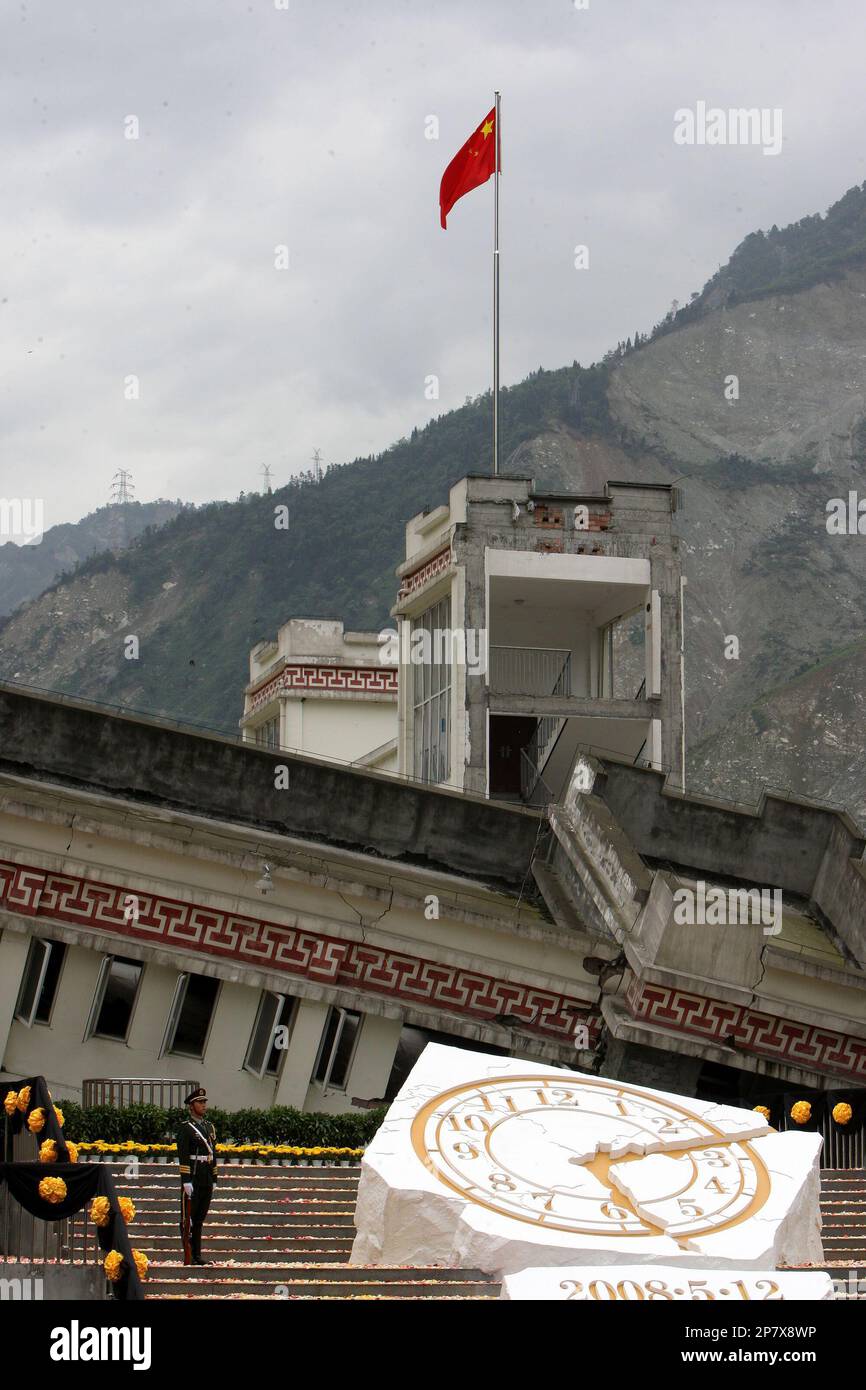A honor guard stands next to a symbolic clock during a commemorative  ceremony to mark the one-year anniversary of Wenchuan earthquake at the  collapsed Xuankou Middle School at Yingxiu township in Wenchuan