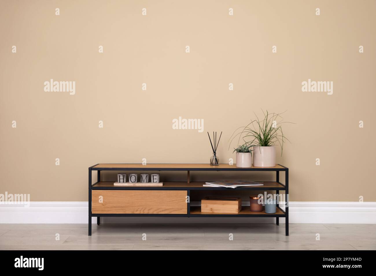 Modern TV cabinet with decor near beige wall. Space for design Stock Photo