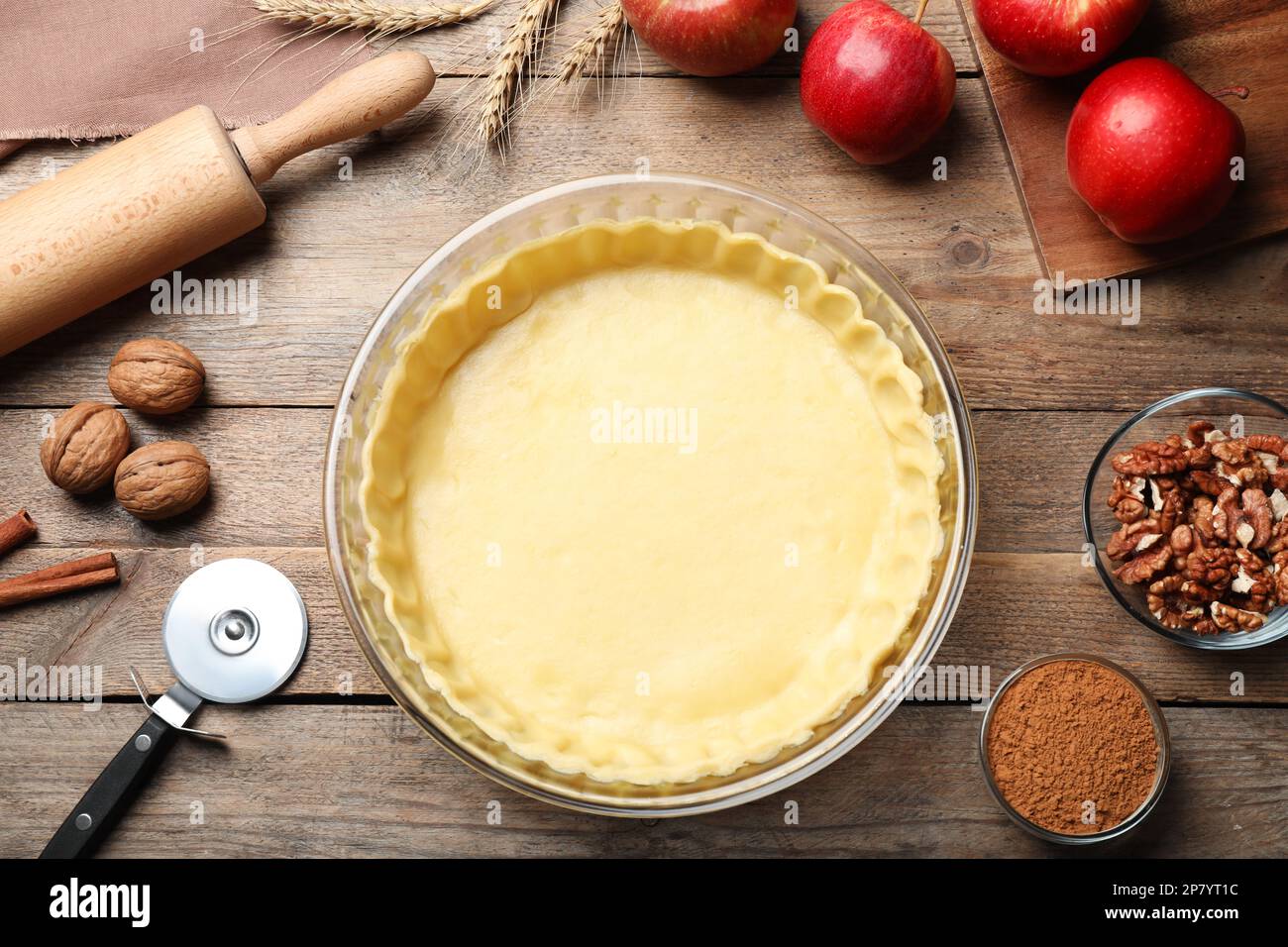 Flat lay composition with raw dough and ingredients for apple pie on wooden table Stock Photo