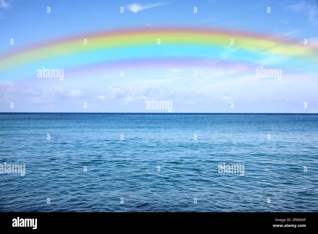 Beautiful rainbow in blue sky over sea on sunny day Stock Photo - Alamy