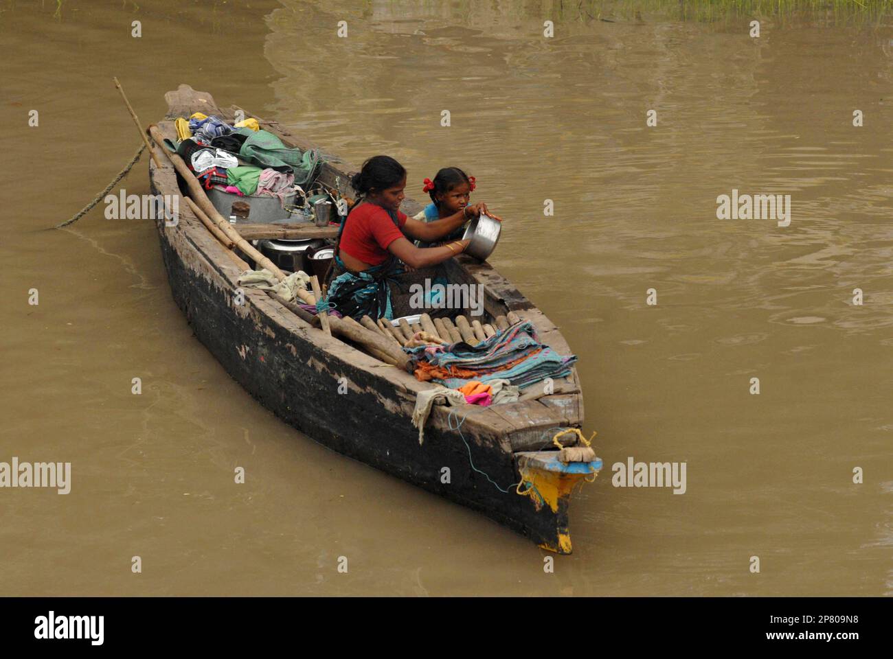 A family lives on a boat on the outskirts of Vijayawada in Krishna district, about 250 kilometers (155 miles) form Hyderabad, India, Friday, Oct. 9, 2009. The worst floods in a century to hit the southern Indian states of Karnataka and Andhra Pradesh destroyed or washed away millions of hectares (acres) of cropland and contaminated grain stocks in millions of homes. (AP Photo/Mahesh Kumar A) Stock Photo