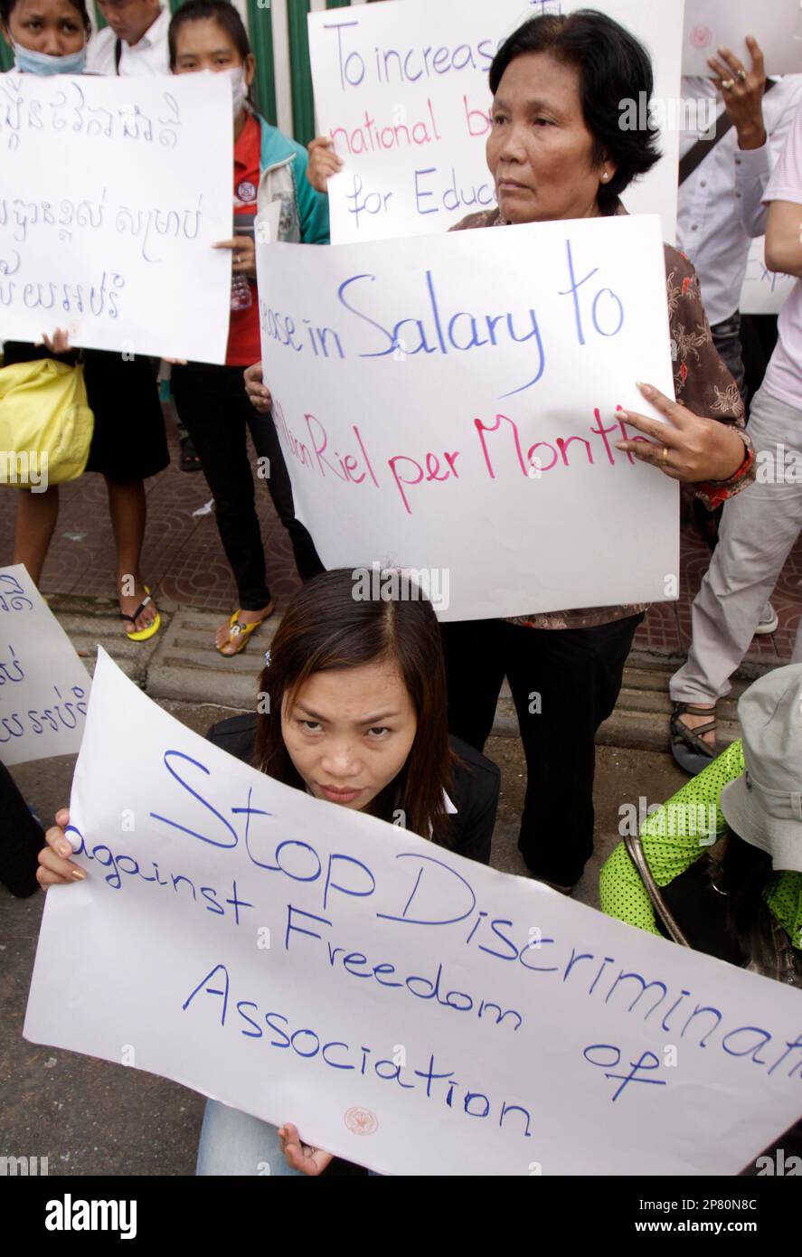 Cambodian teachers holding banners with slogans demanding the