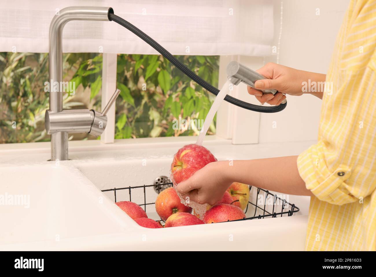 Woman washing apples under tap water in kitchen sink, closeup Stock