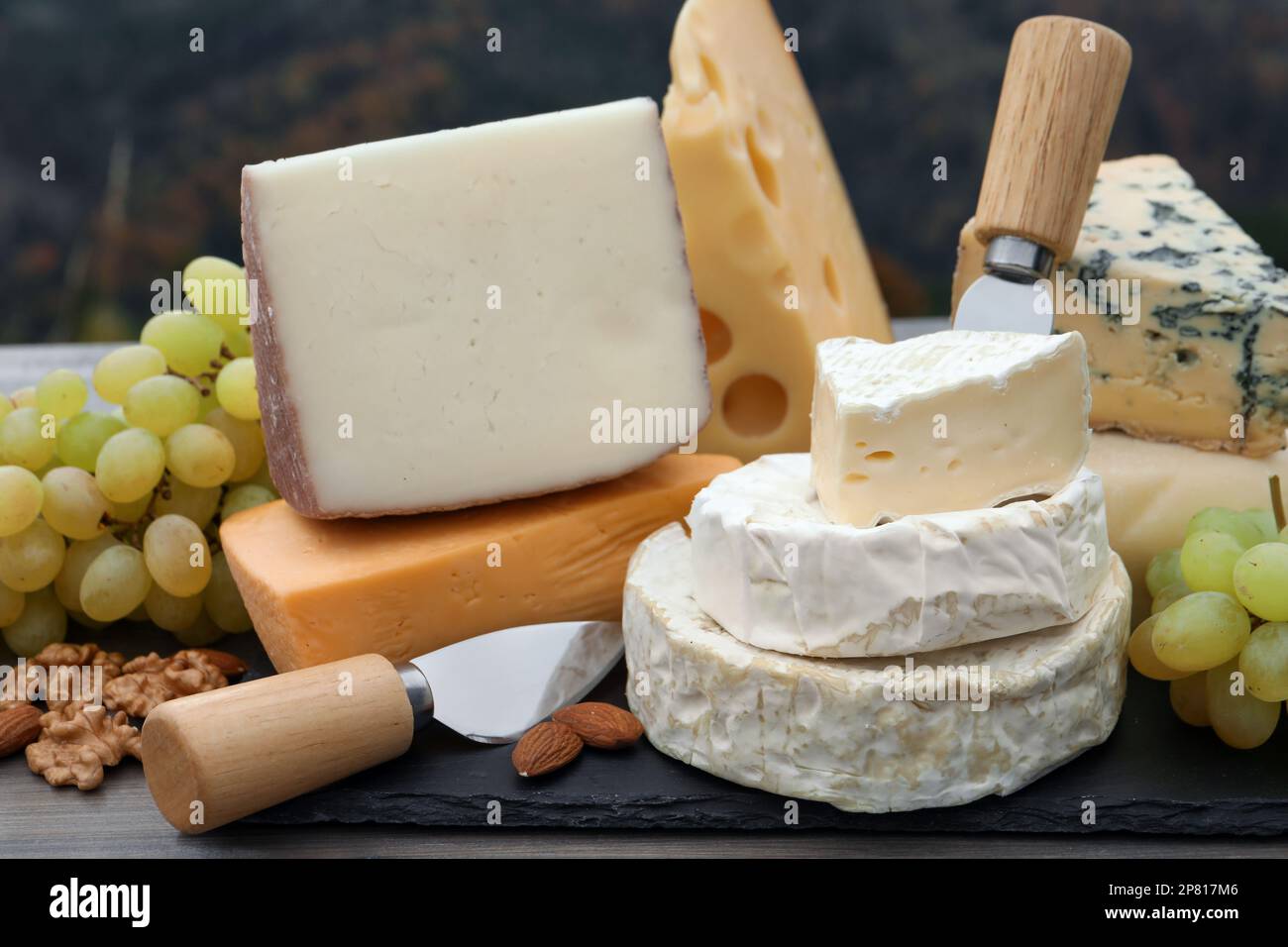 Different types of delicious cheeses and snacks on wooden table ...