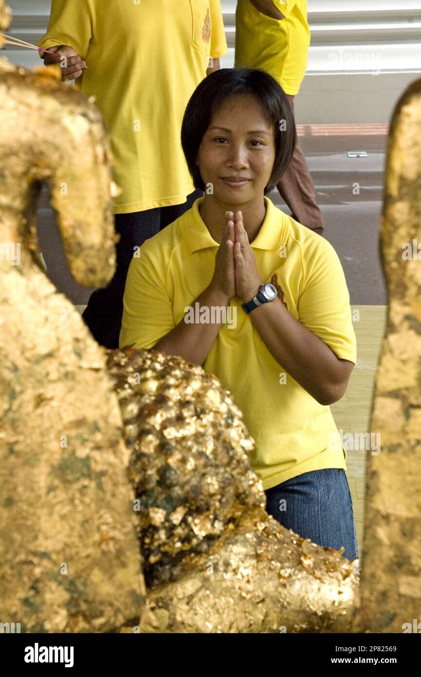 Thai woman offers a traditional wai or clasped hand greeting at Wat Po, one of Bangkok's major Buddhist temples Stock Photo