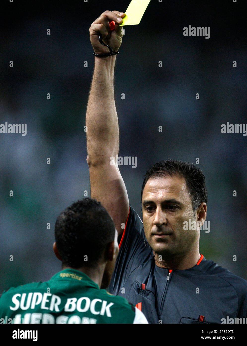 Referee Olegario Benquerenca shows Sporting's striker Liedson a yellow card during their