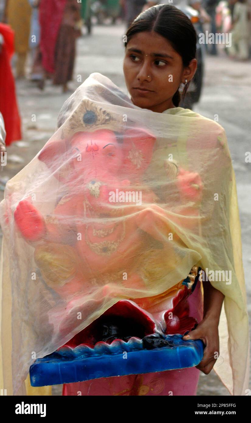 A girl carries an idol of the elephantheaded Hindu god Ganesh on the