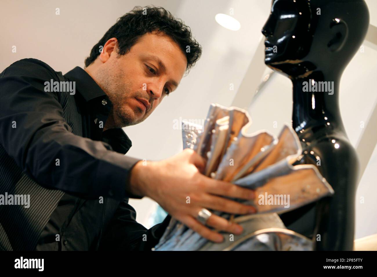 FILE - In this April 28, 2009 file photo, Lebanese fashion designer Zuhair  Murad fixes a dress on a mannequin in his showroom in Beirut, Lebanon. Amid  a largely conservative Muslim Arab
