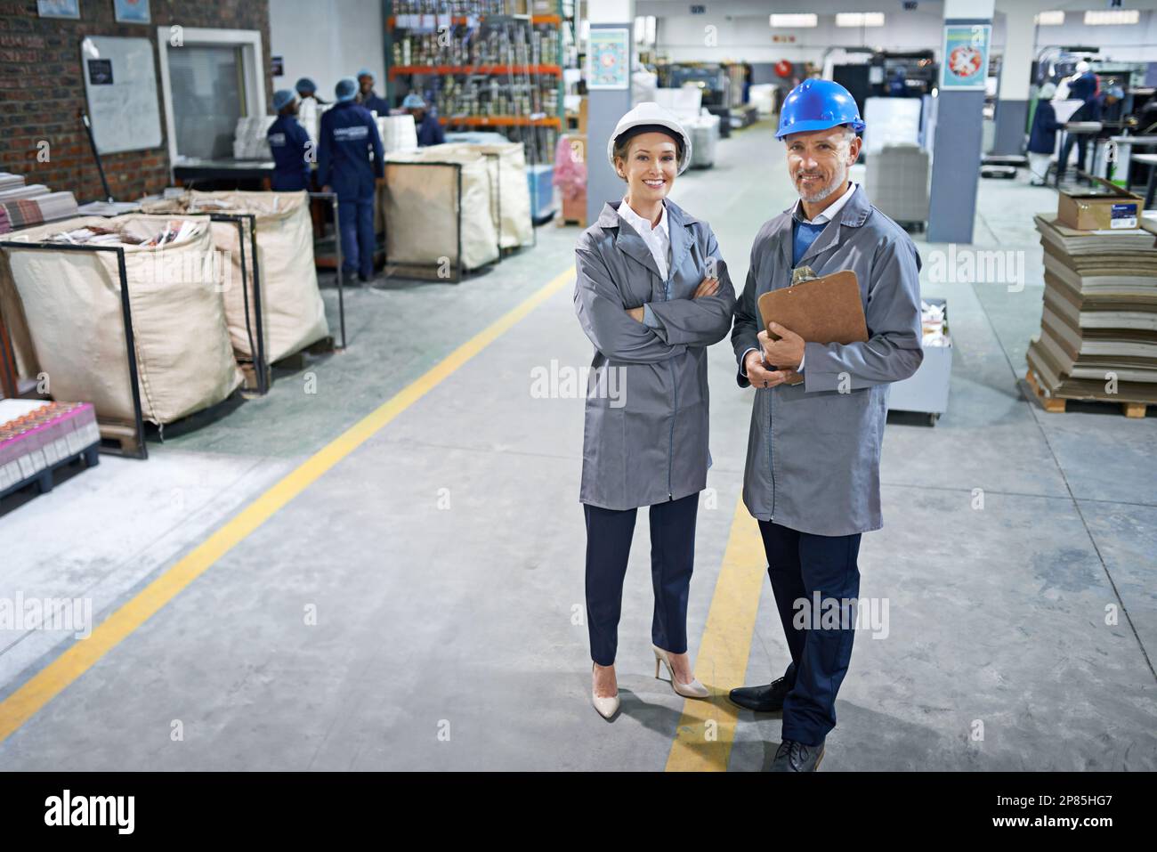 From printing to packaging, we can do it all. Portrait of two managers standing inside a printing and packaging plant. Stock Photo