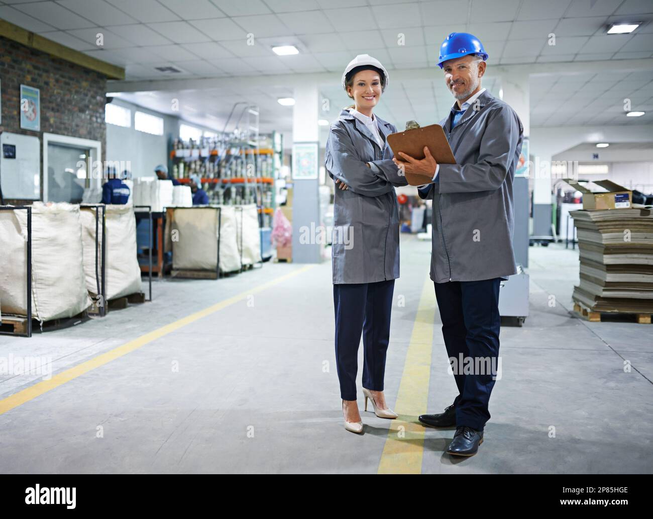 We get every job done to spec. Portrait of two managers standing inside a printing and packaging plant. Stock Photo