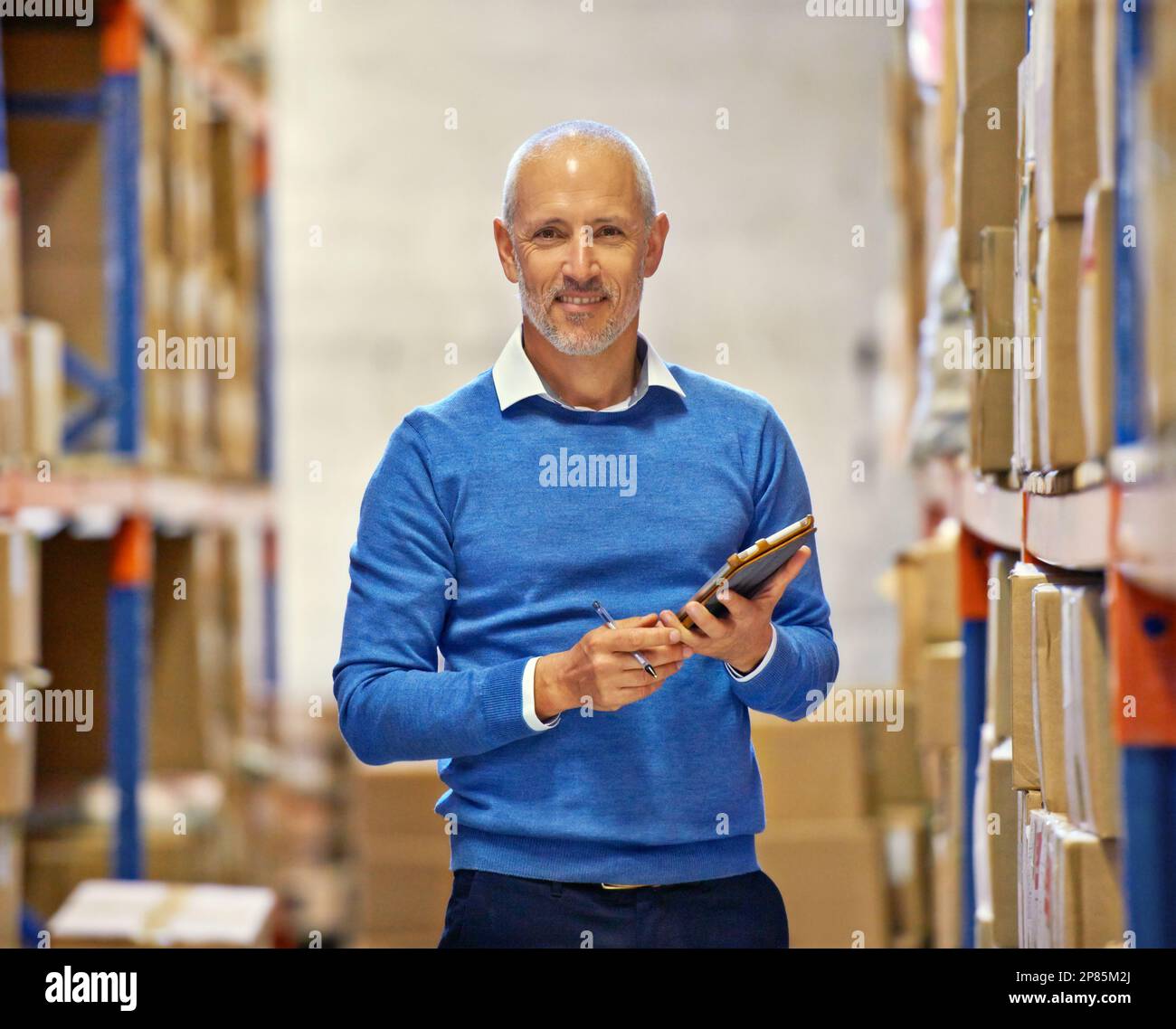 The right man for the job. Portrait of a warehouse manager with a tablet standing amongst shelving. Stock Photo