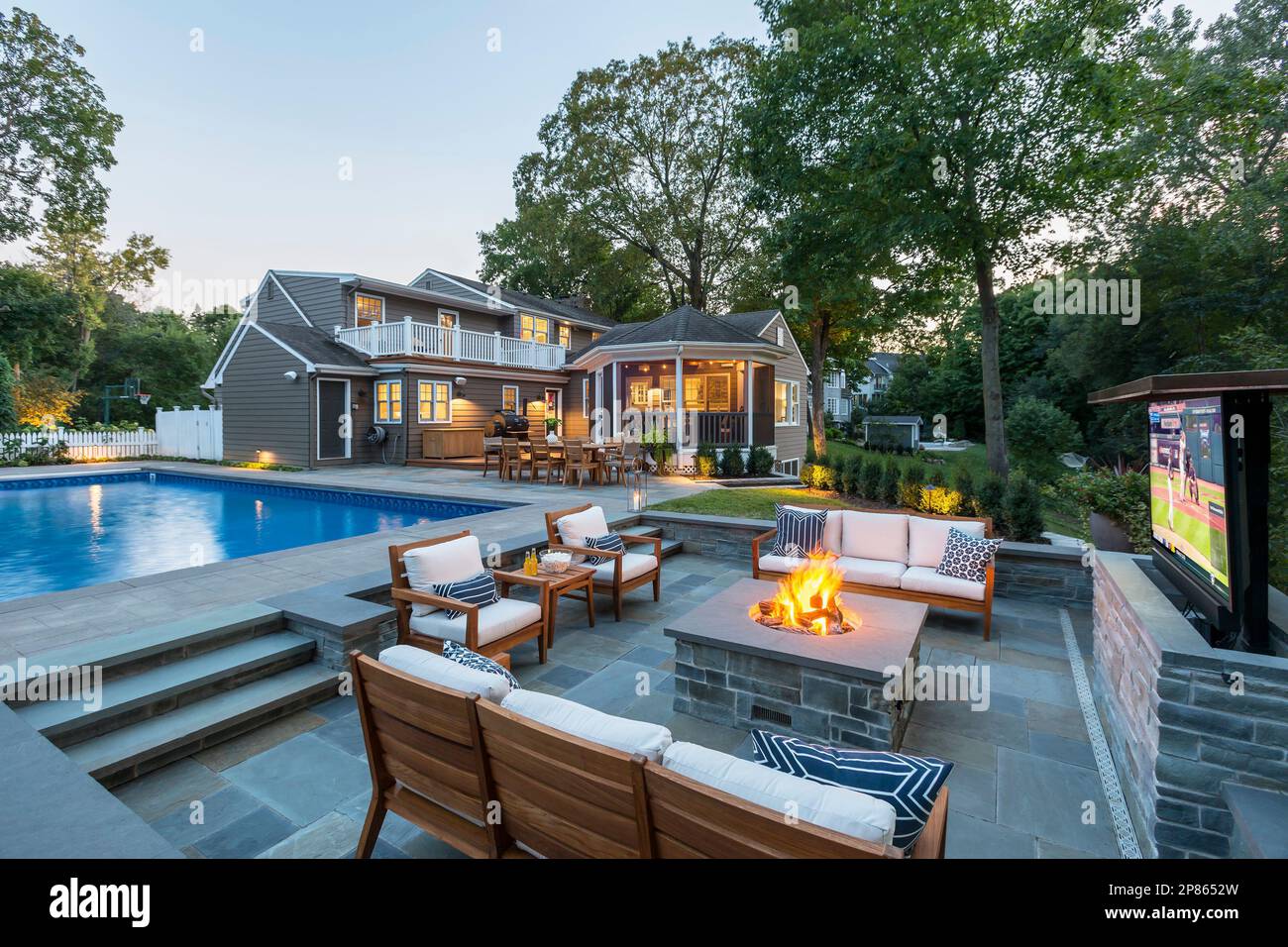 Backyard with sunken firepit and outdoor television next to swimming pool Stock Photo