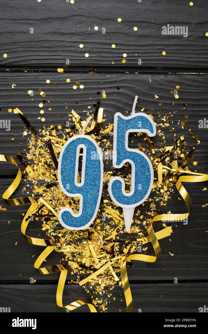 Number 95 Blue Celebration Candle And Gold Confetti On Dark Wooden