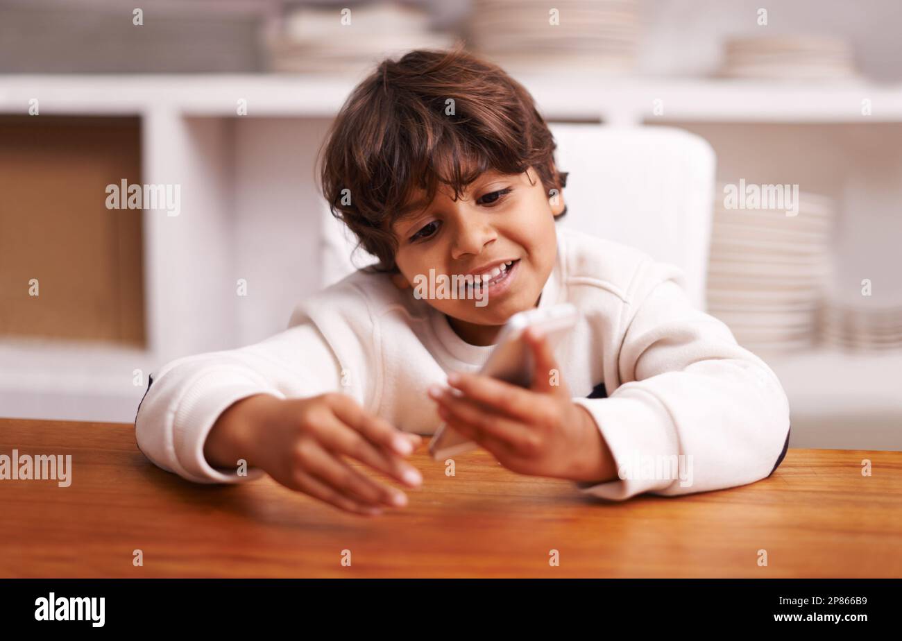 Having fun with his phone. a little boy playing with a smartphone at home. Stock Photo
