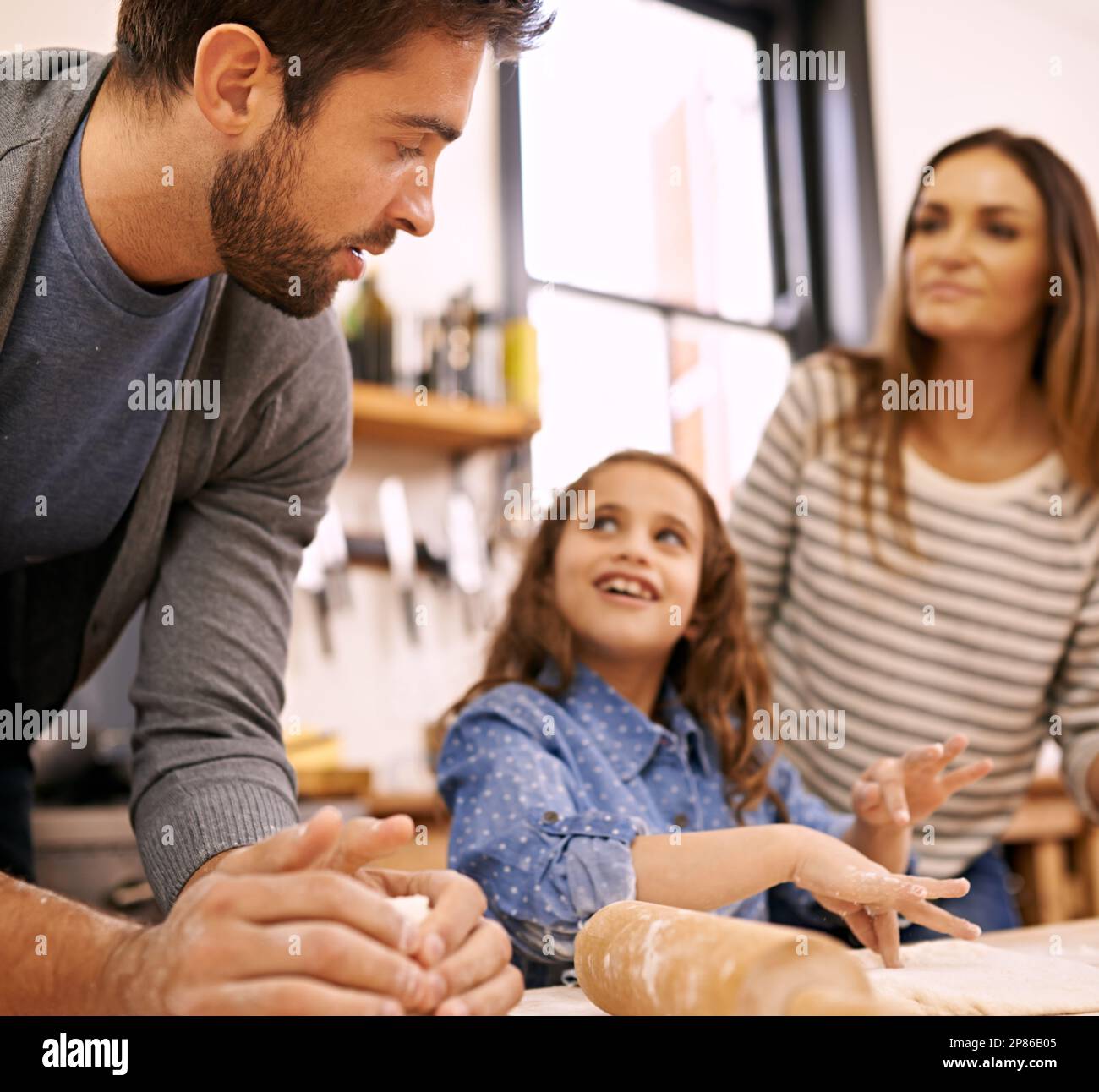 Am I doing ok dad. a happy family of three baking together in the kitchen. Stock Photo