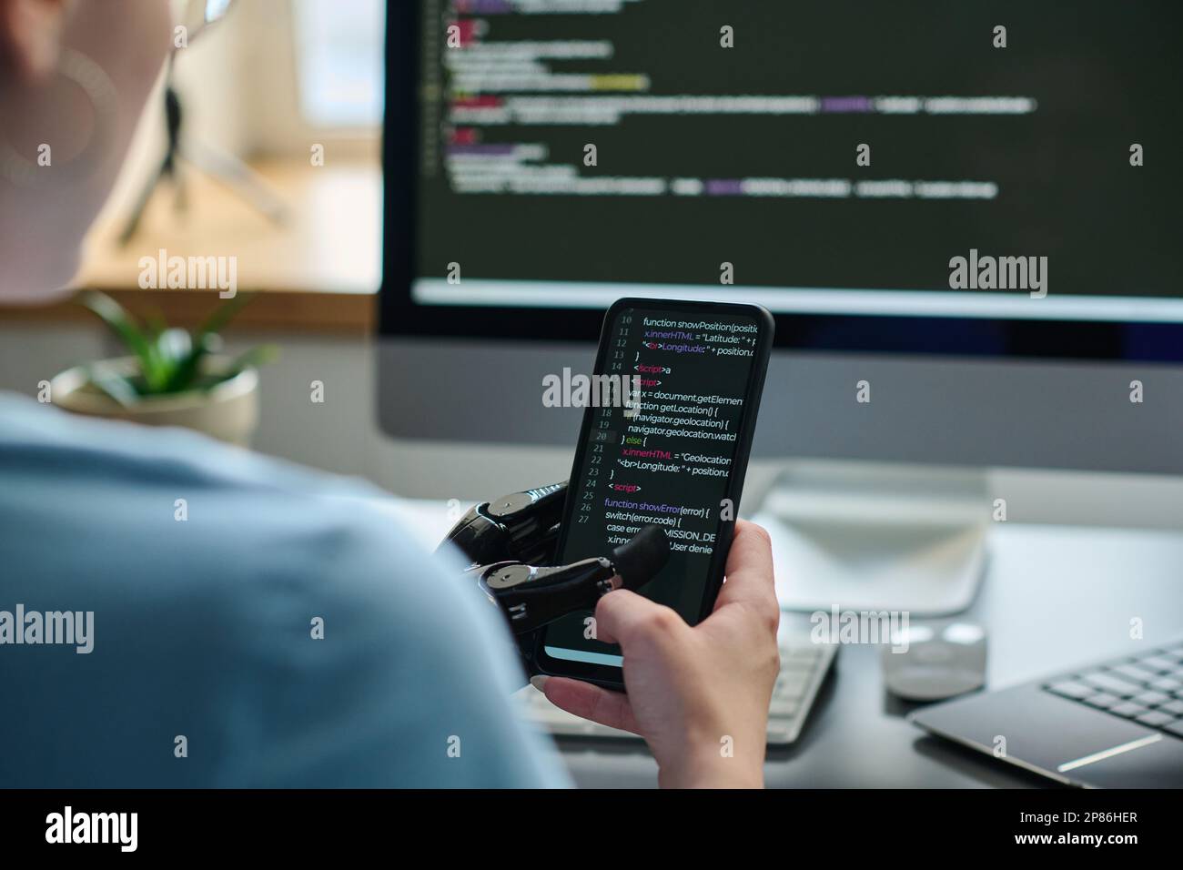 Close-up of IT specialist working with codes on smartphone connecting it with computer and developing software Stock Photo