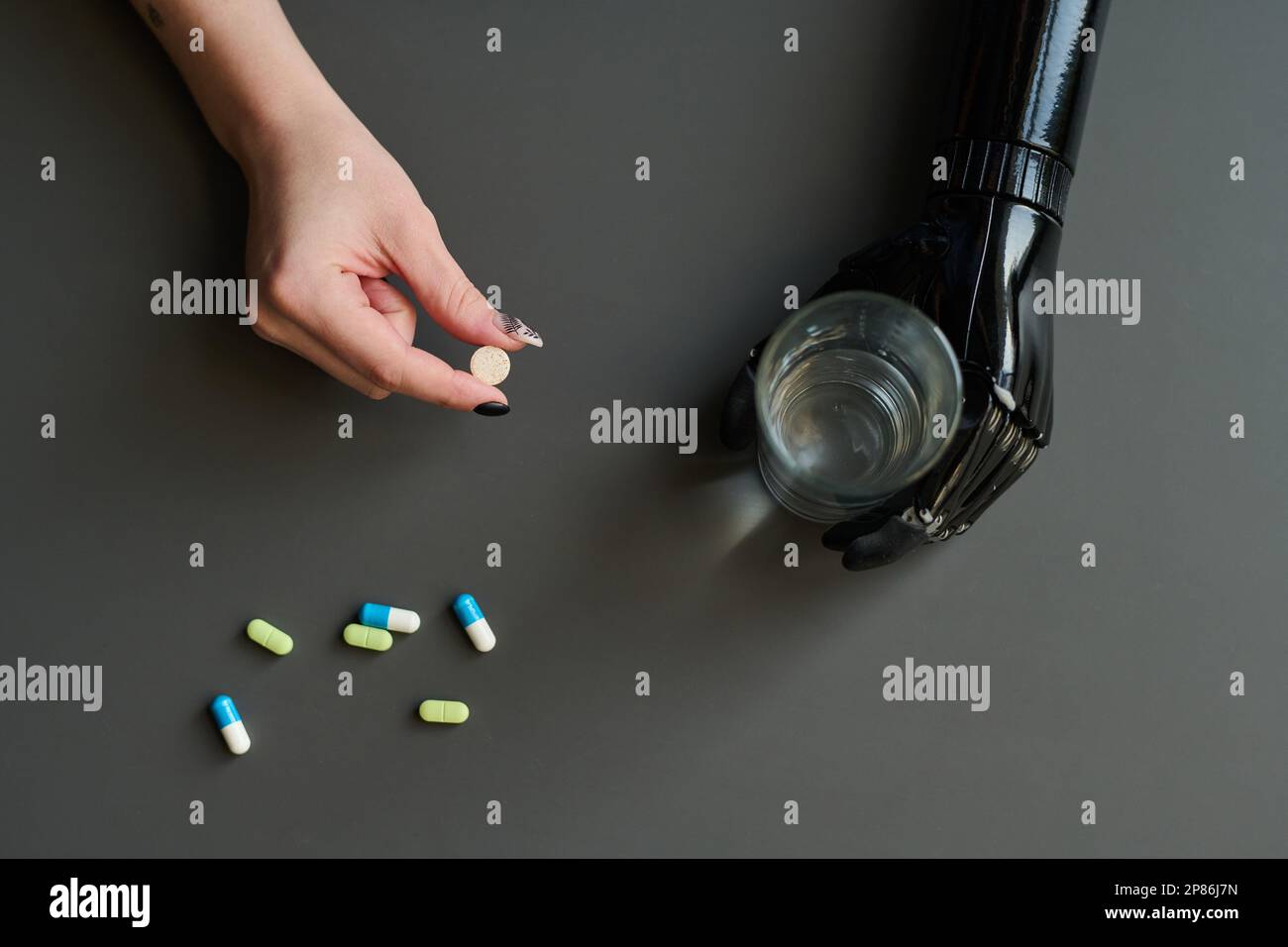 High angle view of woman with prosthetic arm taking pills and drinking water Stock Photo