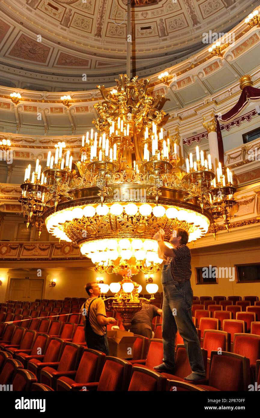 Haustechniker befestigen am Freitag, 7. August 2009, in Dresden, Sachsen, die Lampen am Kronleuchter im Zuschauerraum der Semper-Oper. Jaehrlich in der spielfreien Zeit im Sommer werden die 258 Gluehbirnen und Lampenschalen des