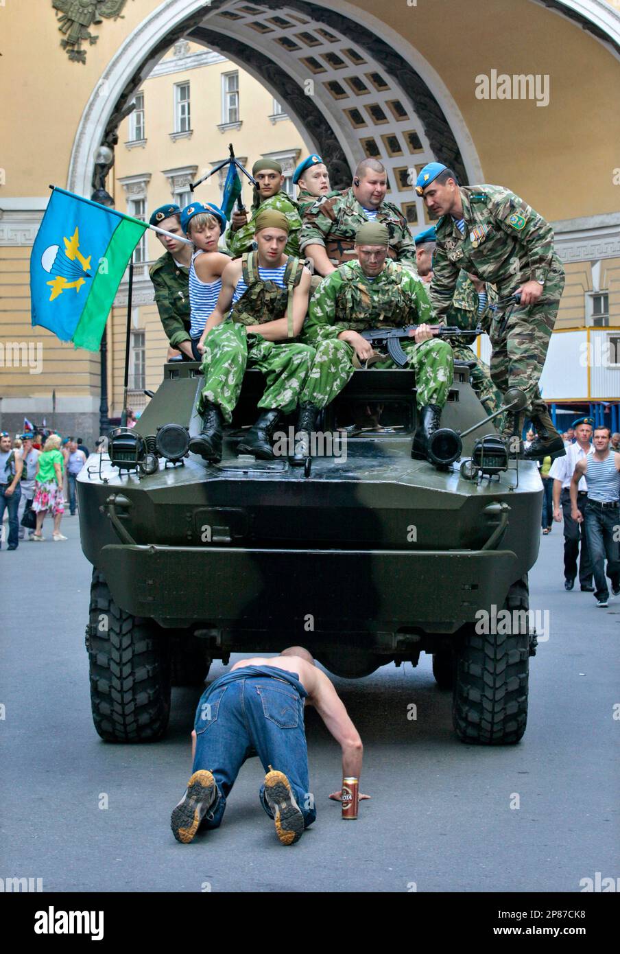 Former paratroopers riding atop an APC look at one of them falling to