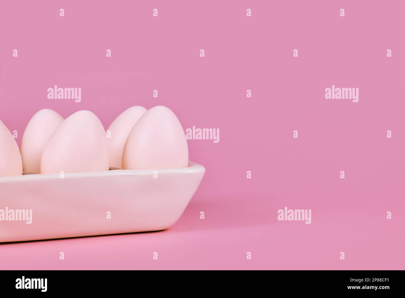 Simple one colored Easter eggs in egg tray on pink background with copy space Stock Photo