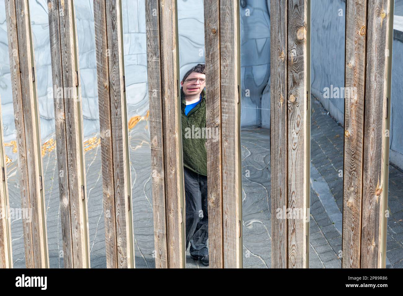 Distorted specular image of a person within a structure of wooden