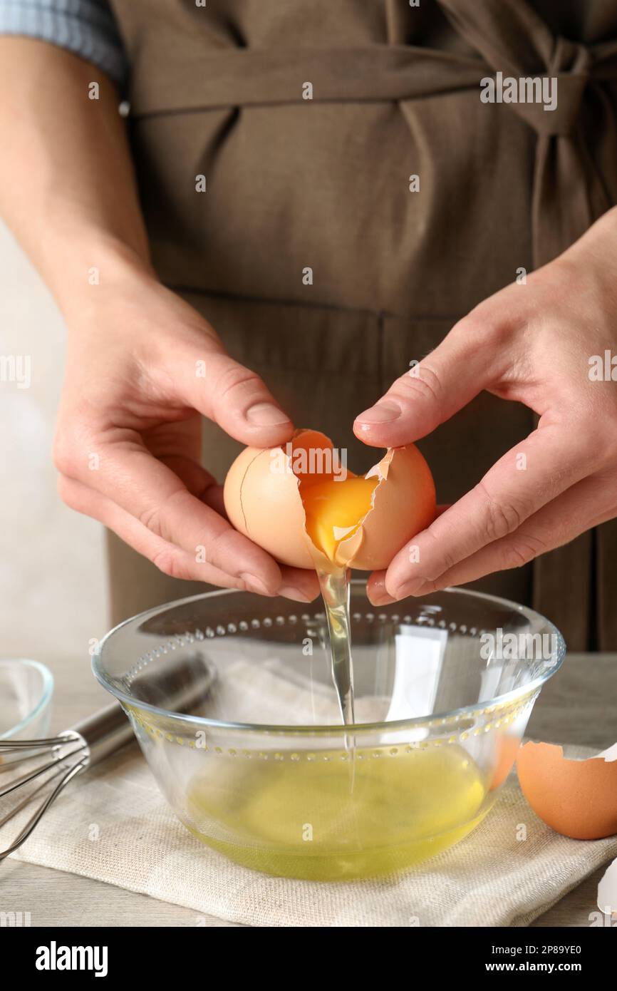 https://c8.alamy.com/comp/2P89YE0/woman-separating-egg-yolk-from-white-over-glass-bowl-at-light-wooden-table-closeup-2P89YE0.jpg