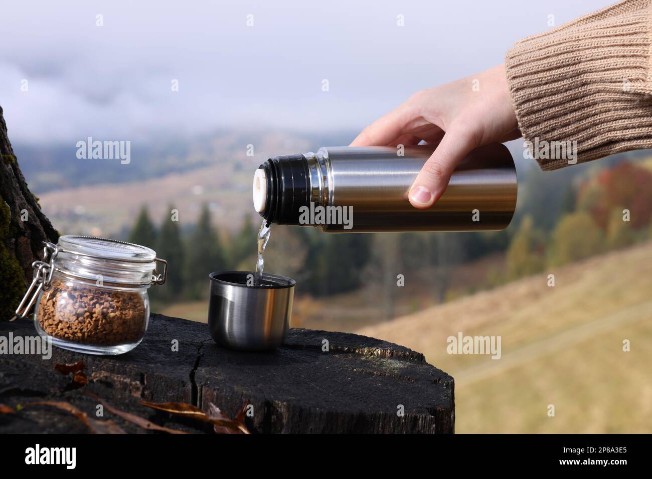 Woman pouring hot water into cup with instant coffee in mountains, closeup Stock Photo Alamy