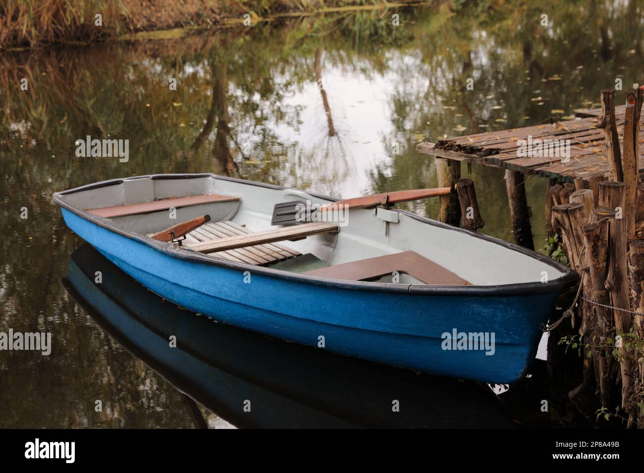 Light blue wooden boat with oars on lake near pier Stock Photo - Alamy