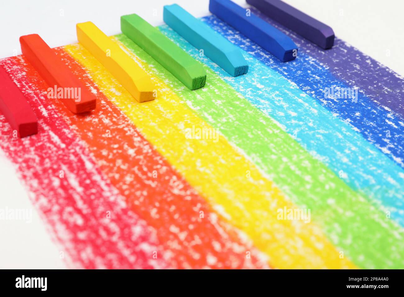 Colorful pastel chalks on rainbow painting, closeup. Drawing materials