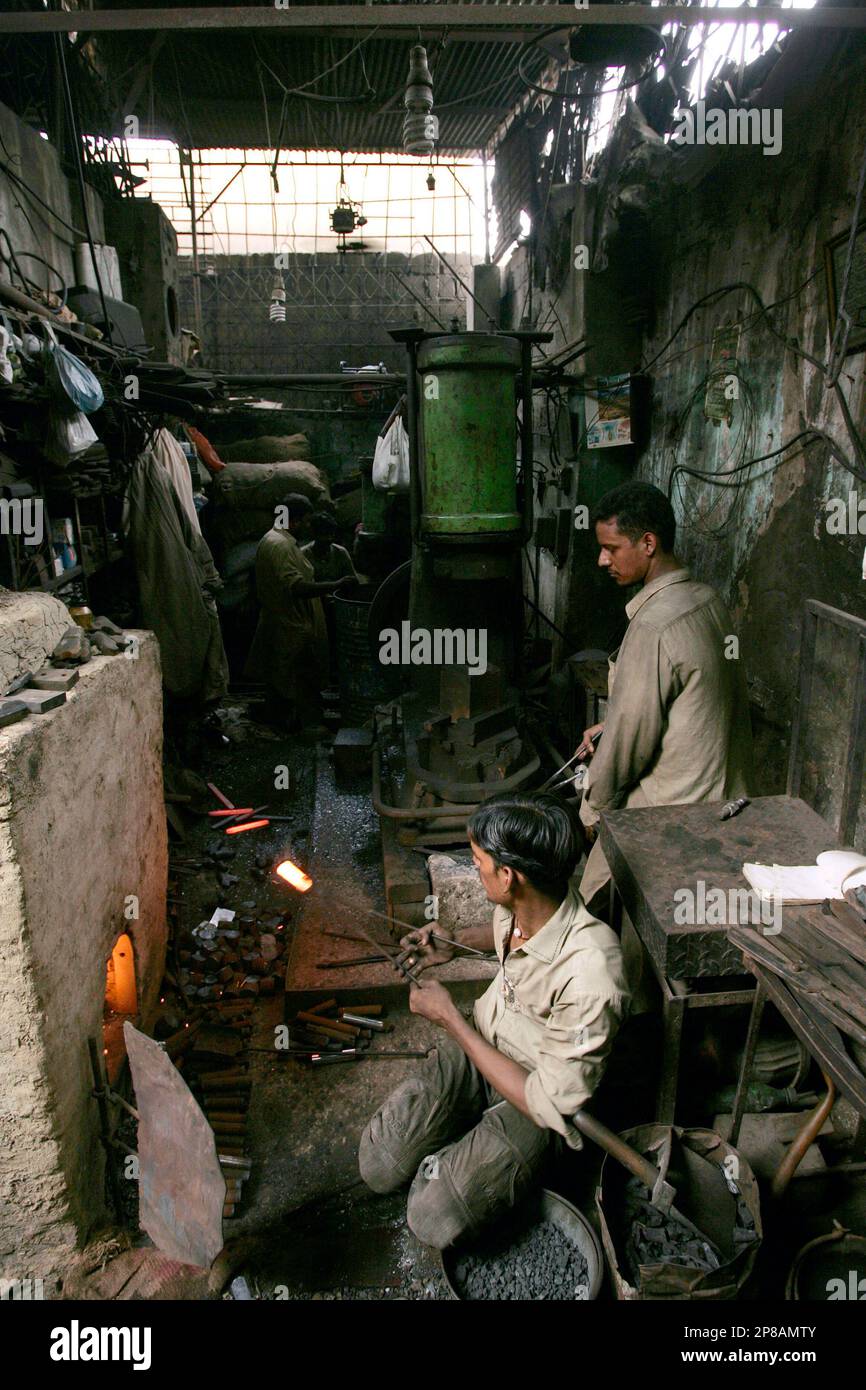 Pakistani workers prepare iron tools in a conventional furnace in