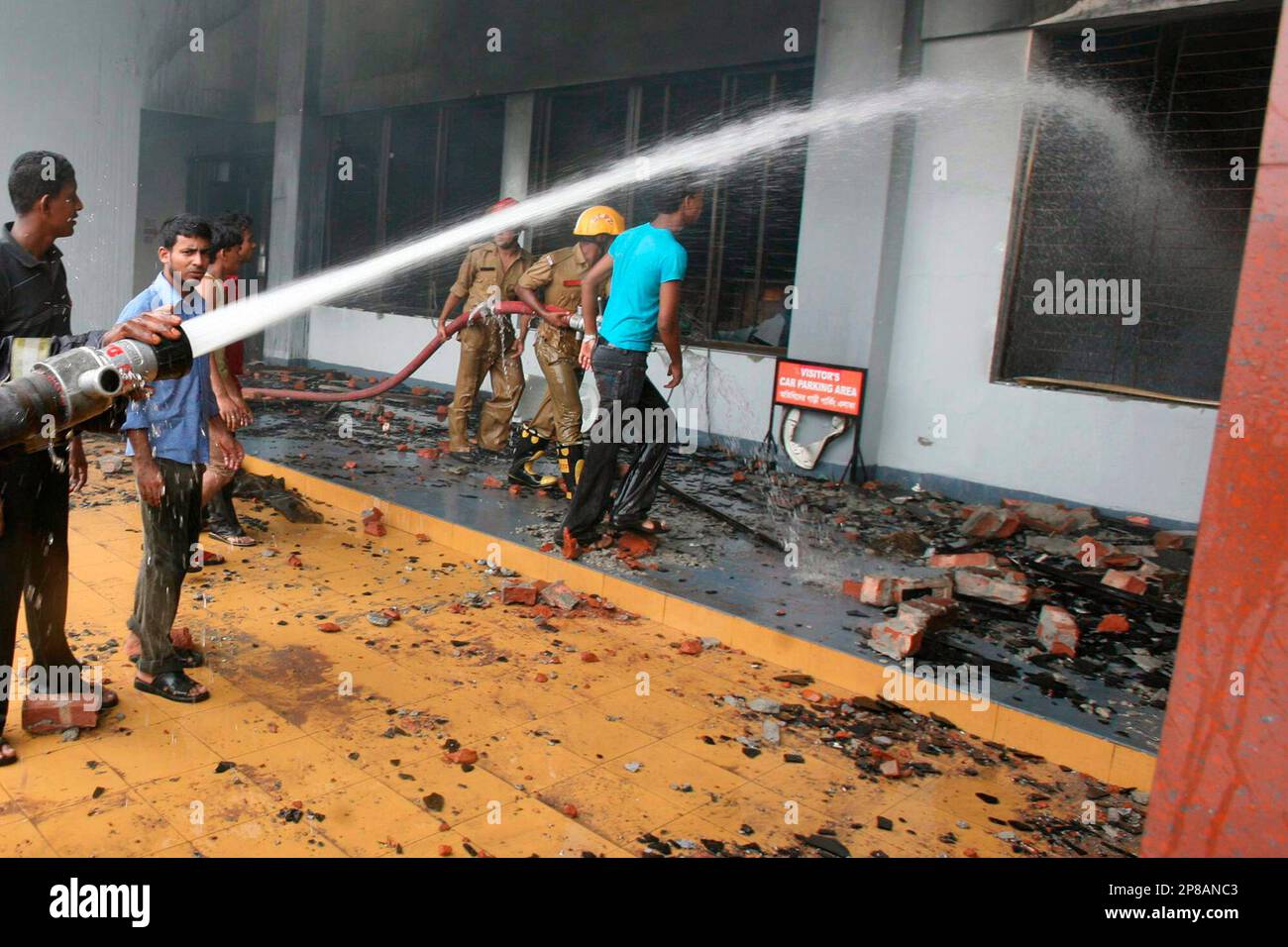 Firemen and workers spray water inside a garment factory in Ashulia ...