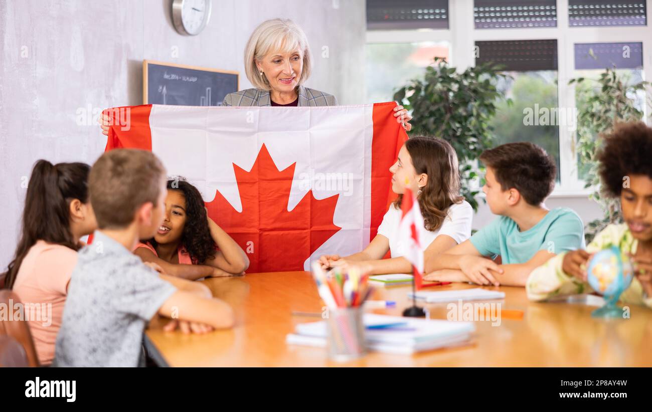 Female teacher showing canadian flag to kids in geography class Stock Photo