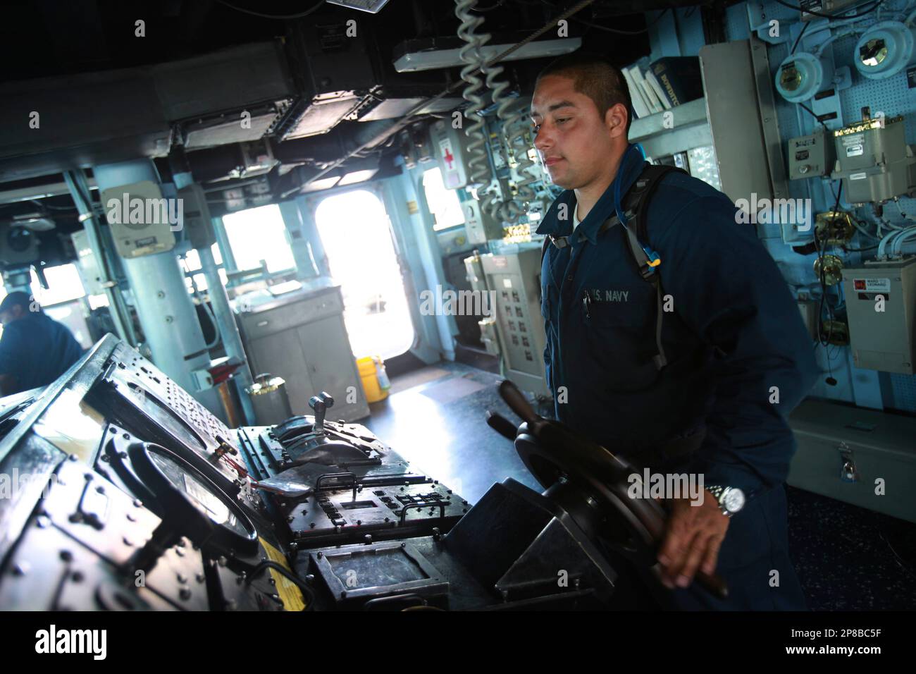 U.S Navy soldier stands on the bridge as he steers the USS Arleigh 