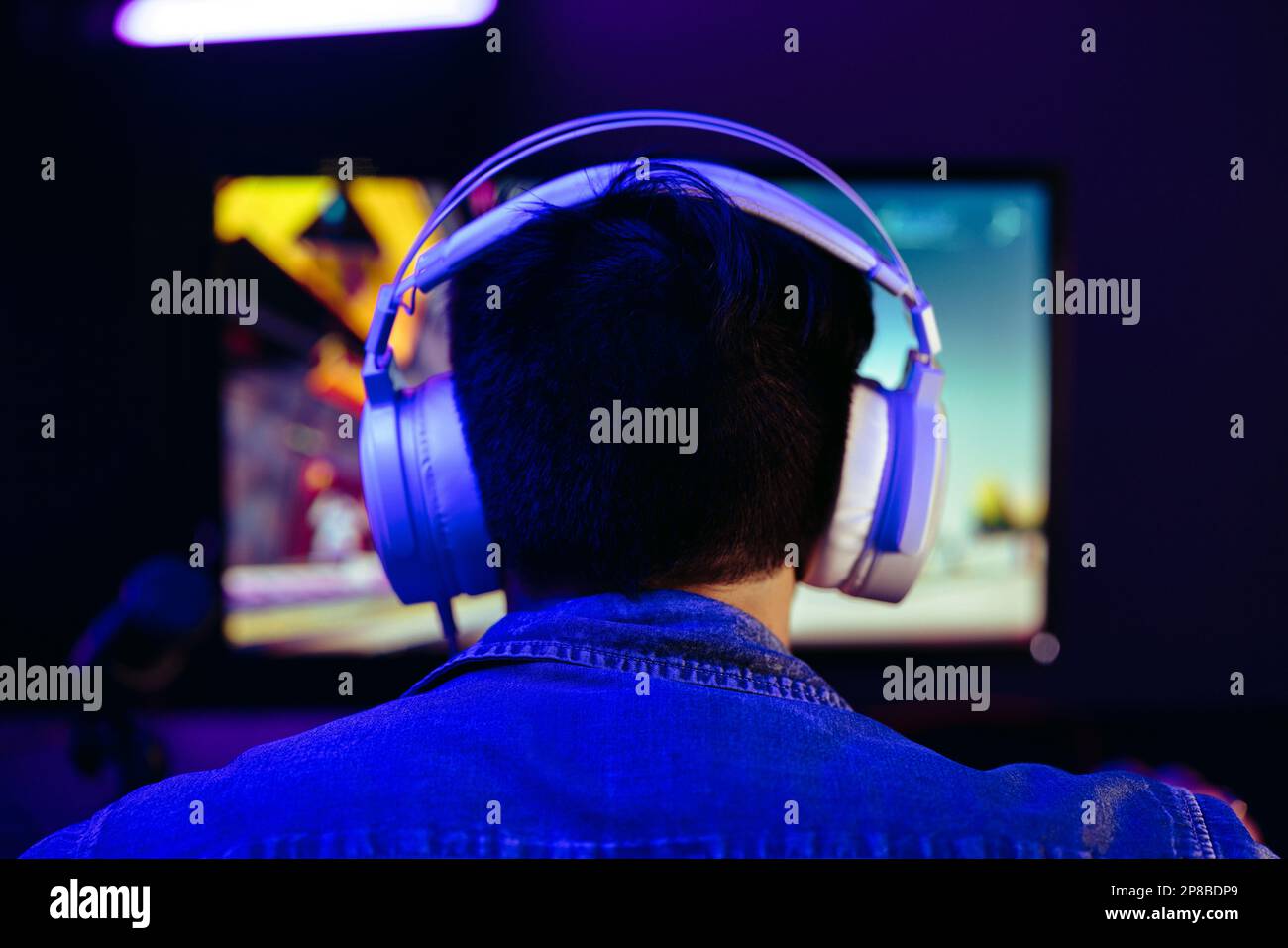 Young man getting into the vibrant world of online gaming. Computer gamer immersing himself in a first-person shooter gameplay, delivering electrifyin Stock Photo