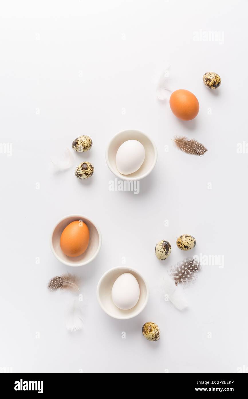 Different eggs with feathers for Easter on white background Stock Photo