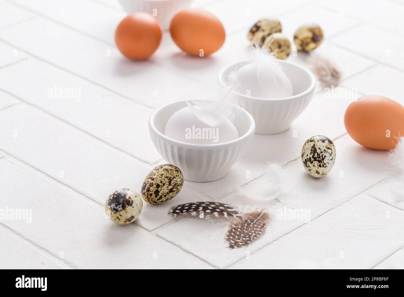 Different eggs with feathers for Easter on white background Stock Photo