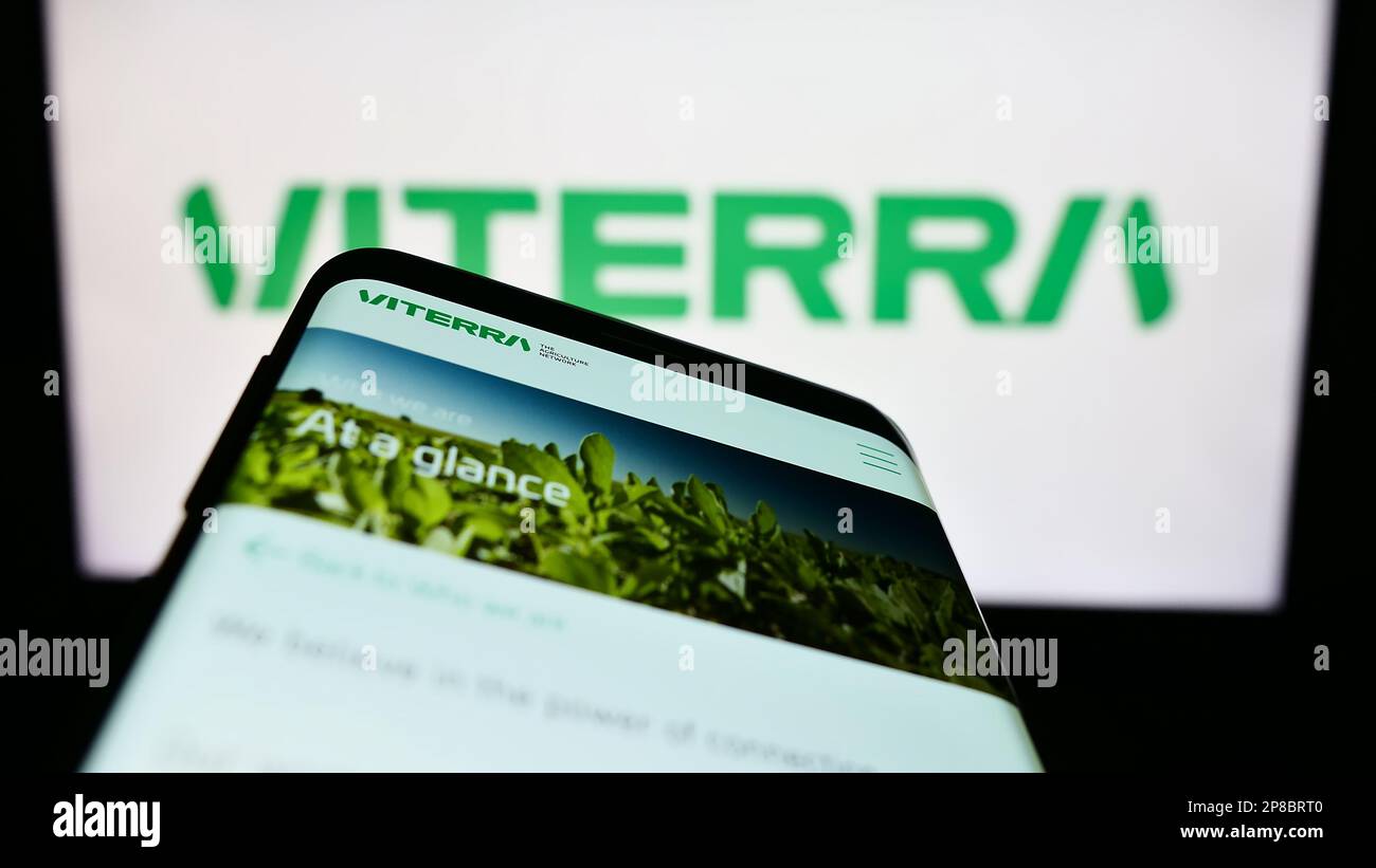 Mobile phone with website of commodity trading company Viterra Limited on screen in front of business logo. Focus on top-left of phone display. Stock Photo